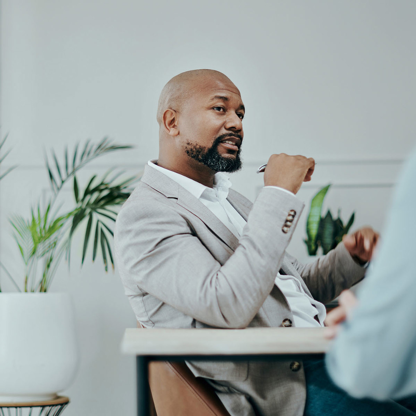 A man in a suit sat at a table having a conversation with a lady wearing blue