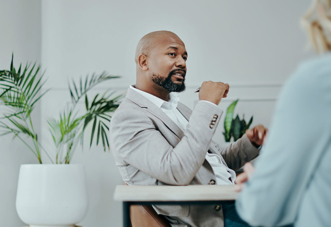 A man in a suit sat at a table having a conversation with a lady wearing blue