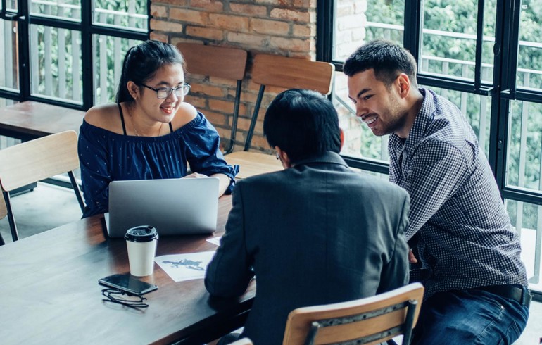 A group of three colleagues talking casually around a table