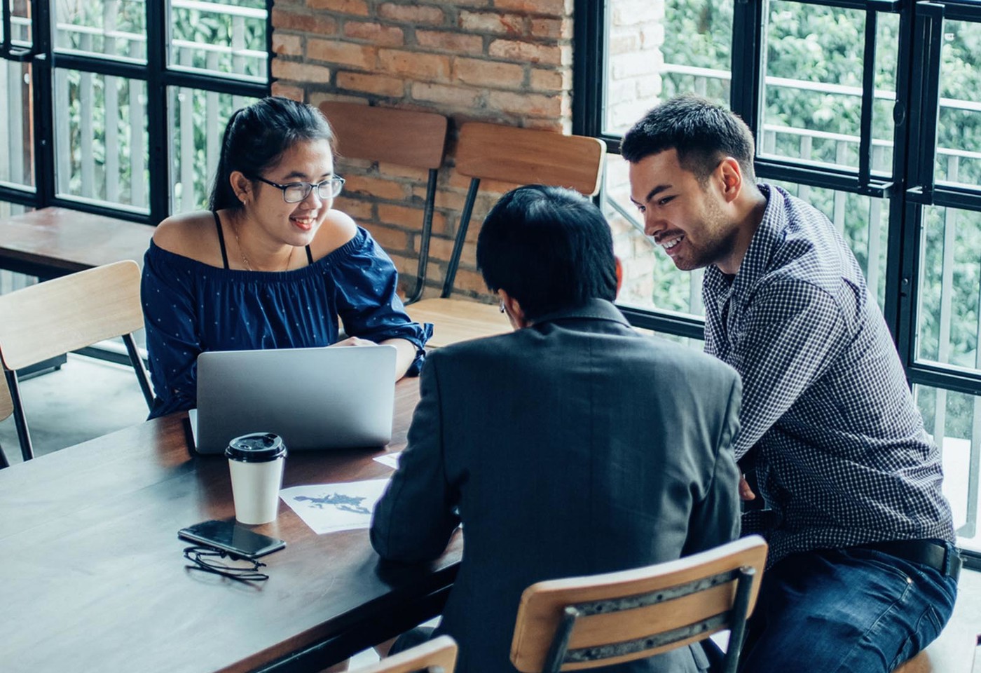 A group of three colleagues talking casually around a table