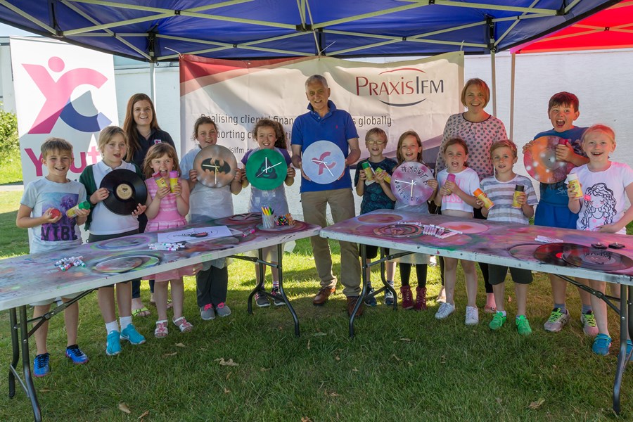 11 children from the Guernsey Youth Commission posing around an arts and crafts table at a PraxisIFM sponsored event