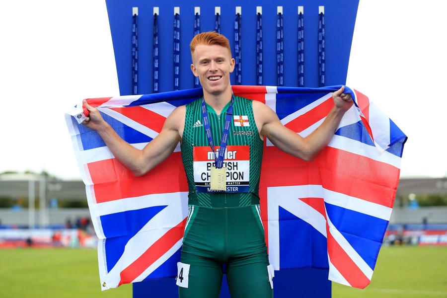 Alastair Chalmers posing at the CommonWealth Games while holding up a GB flag