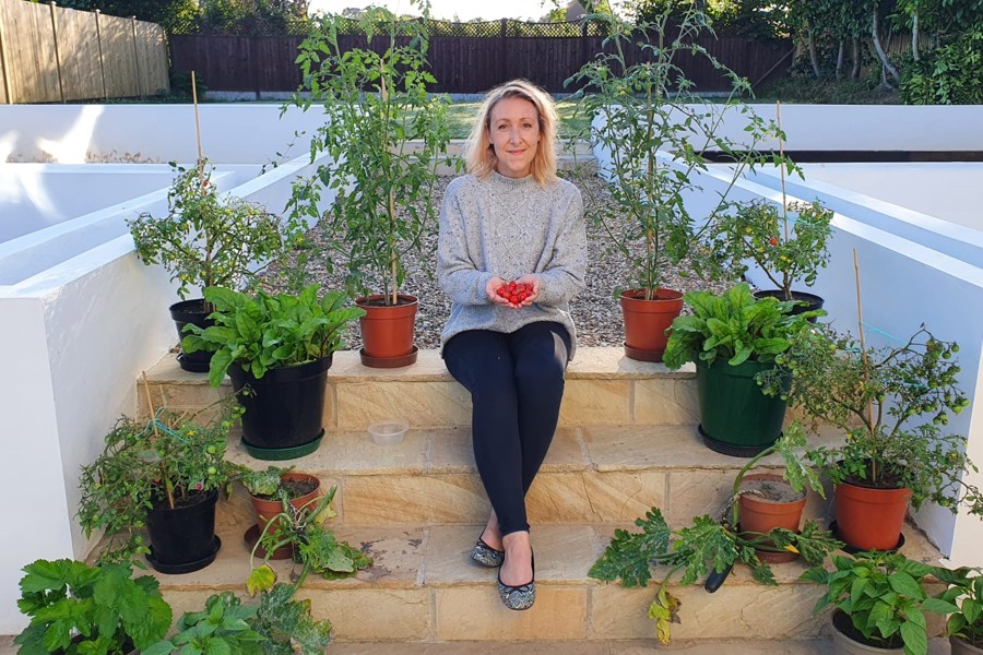 Ruth O'Hara sat on garden steps with lots of potted plants surrounding her