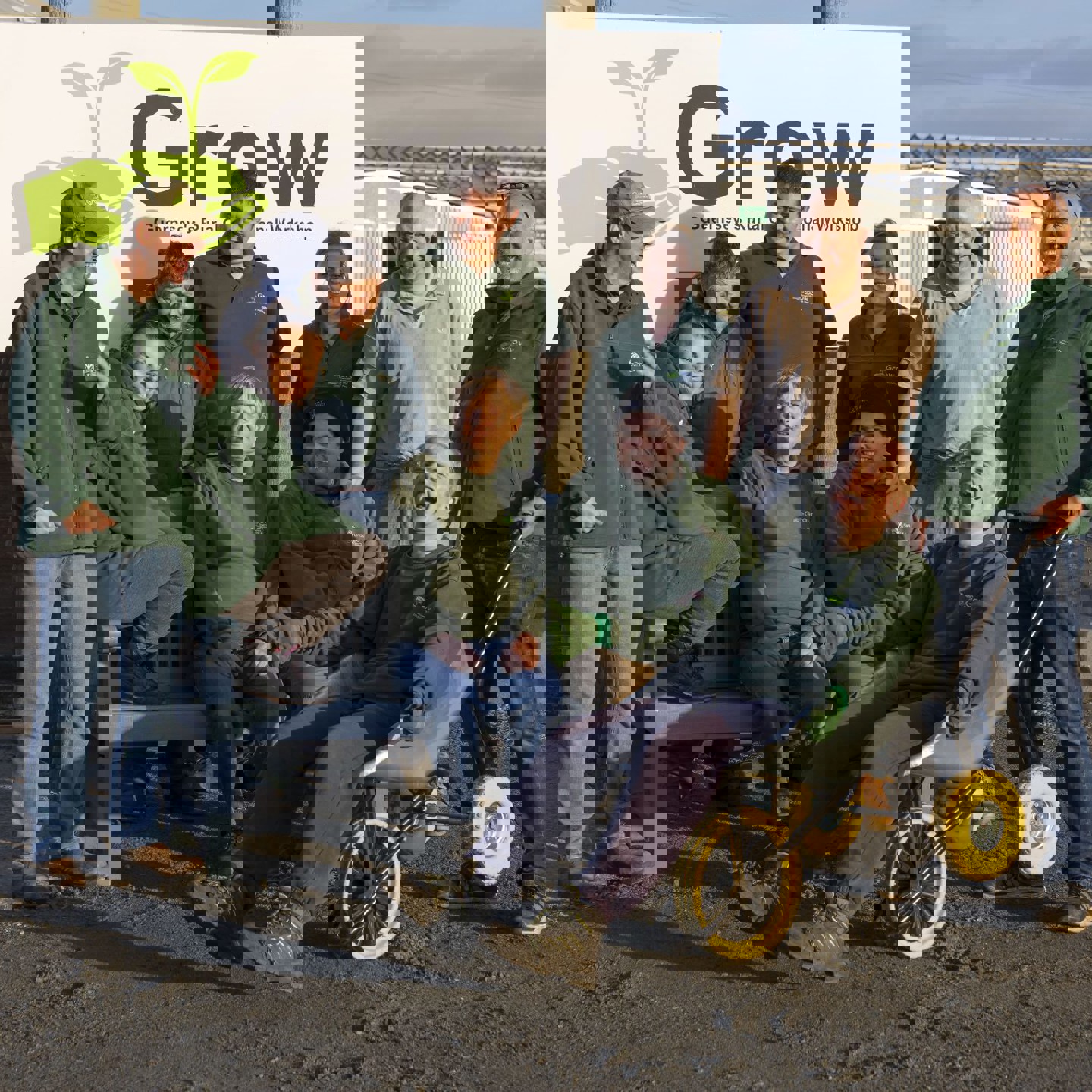 10 volunteers from charity 'Grow' sitting on a bench beside their sign