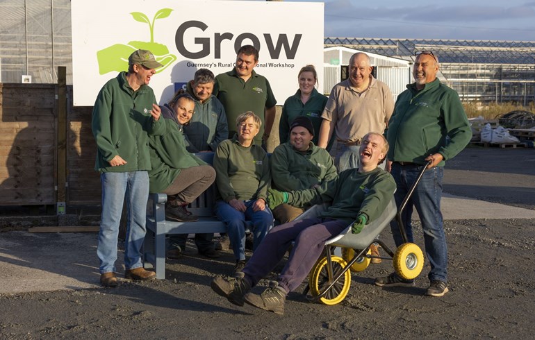 10 volunteers from charity 'Grow' sitting on a bench beside their sign