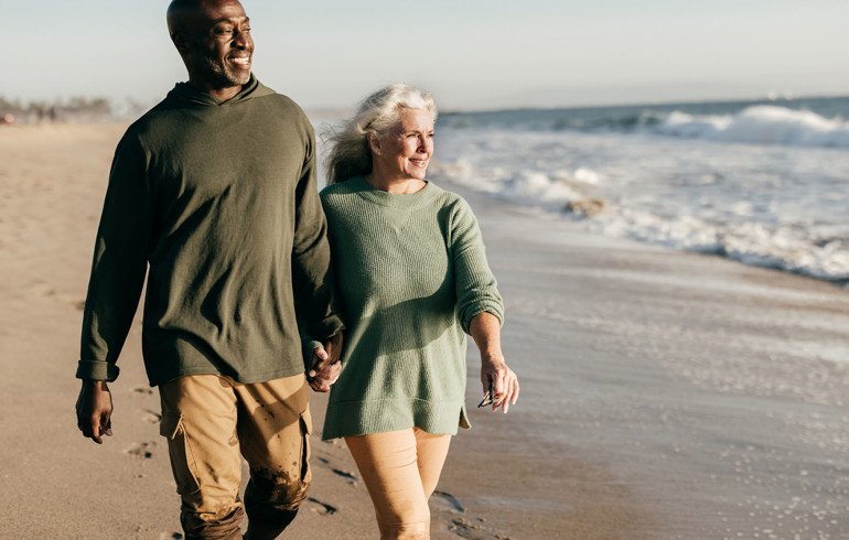 Two elderly people walking on the beach
