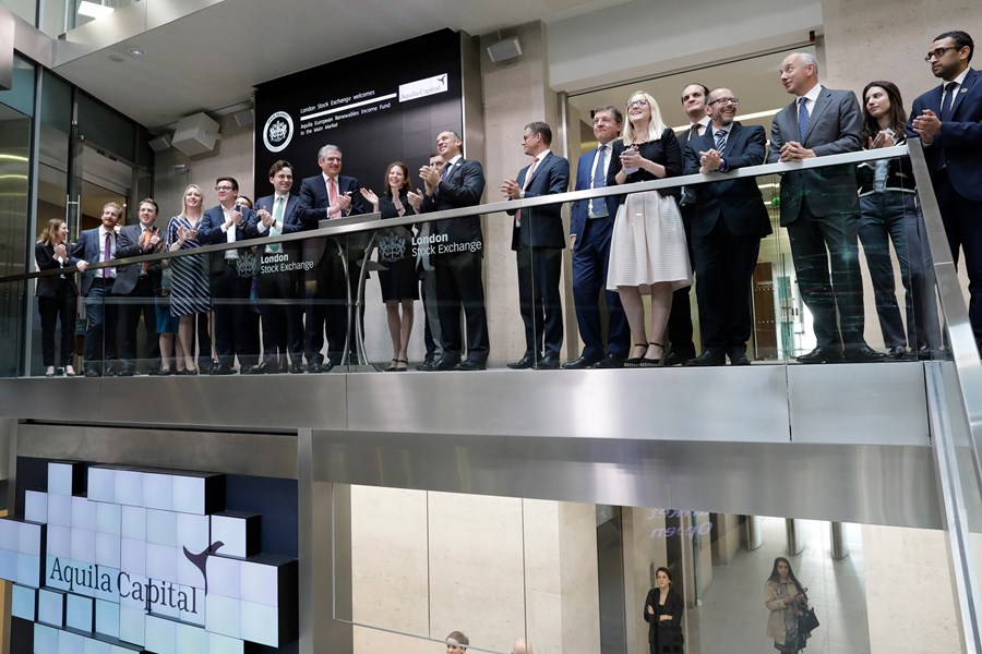 A large group of professionals clapping on a balcony at Aquila Capital