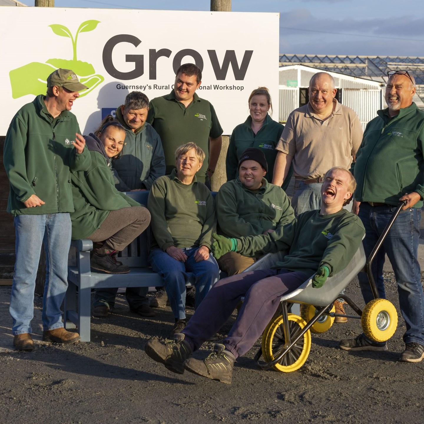 10 volunteers from charity 'Grow' sitting on a bench beside their sign